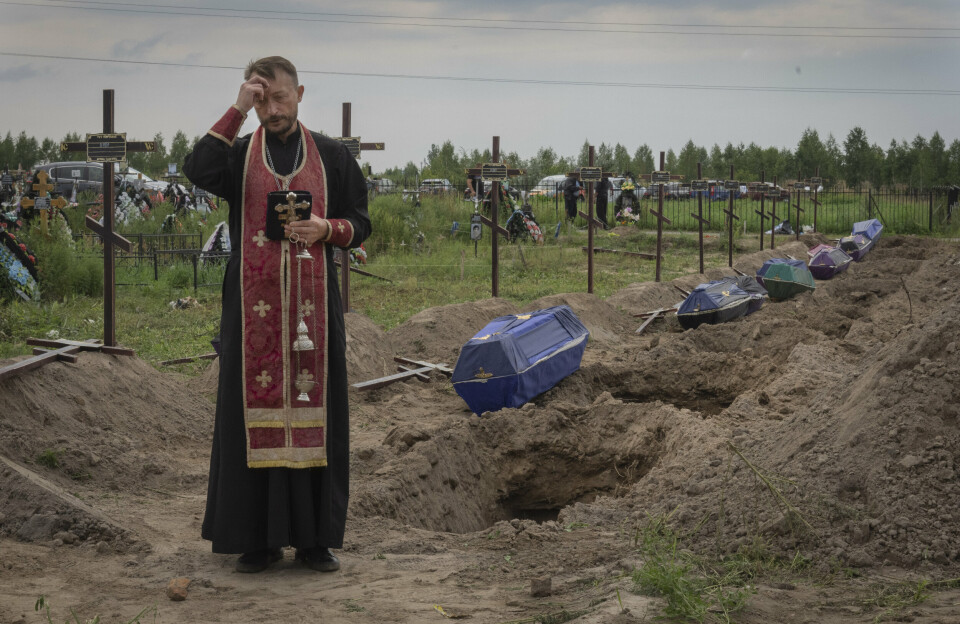UIDENTIFISERTE: En prest gjennomfører en seremoni i forbindelse med begravelse av uidentifiserte lik utenfor Butsja i Ukraina. Bildet er datert 11. august.