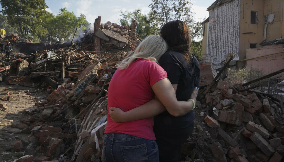 SAMHOLD: To ukrainske kvinner holder rundt hverandre og ser på ruinene av en bygning etter et russiske bombeangrep i Kharkiv sent i august.