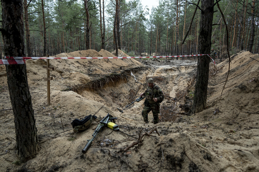 METALLDETEKTOR: En ukrainsk soldat bruker metalldetektor for å inspisere en massegraver utenfor Izium, som Ukraina nylig tok tilbake kontrollen over.