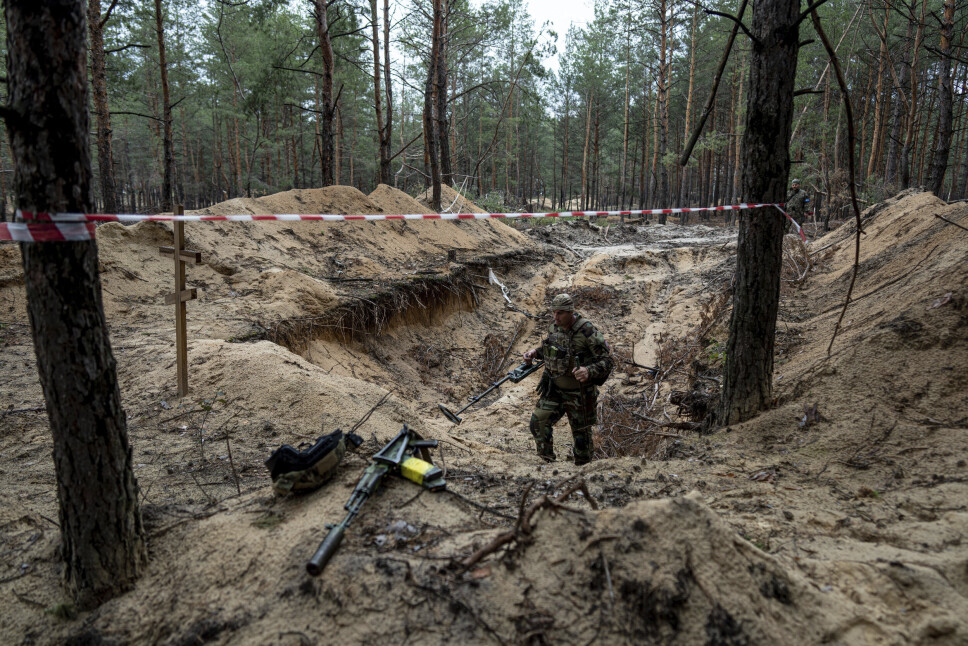 METALLDETEKTOR: En ukrainsk soldat bruker metalldetektor for å inspisere en massegraver utenfor Izium, som Ukraina nylig tok tilbake kontrollen over.