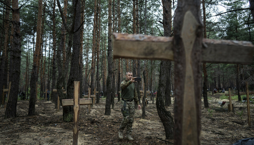 SIKRER BEVIS: Den ukrainske etterforskeren Oleh Kotenko tar bilder og sikrer spor på massegraven som er funnet i Izium.