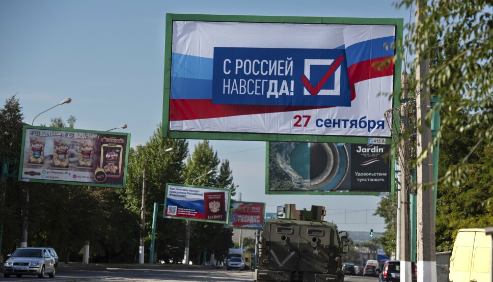 VALGKAMP: Et militærkjøretøy kjører under et skilt med «sammen med Russland for alltid, september 27» i forkant av folkeavstemningen i russisk-kontrollerte Luhansk.