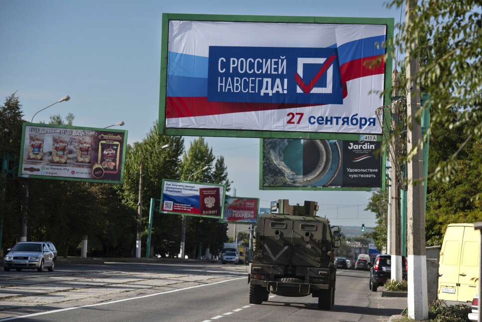 LUHANSK: Et militærkjøretøy passerer en plakat med påskriften «Med Russland, alltid!» i forkant av folkeavstemningen i Luhansk. Fredag innlemmes fylket i Russland.