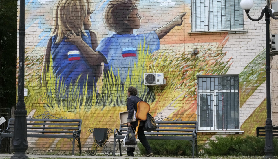 LUHANSK: En mann går forbi graffiti av barn med russiske flagg i Luhansk, som er kontrollert av russisk-støttede opprørere.