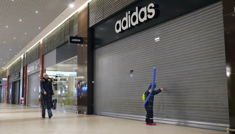 STENGT: Folk går forbi stengte Adidas, Reebok og andre butikker i et kjøpesenter i St. Petersburg, Russland, 24. mars 2022.