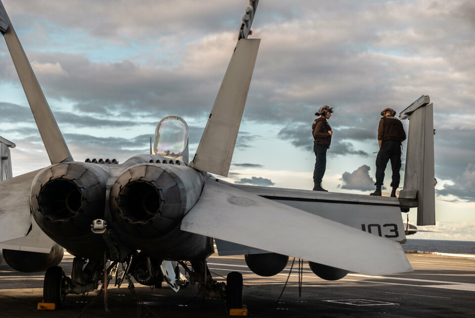 VEDLIKEHOLD: Den amerikanske marinens flyteknikere står på vingen til en F/A-18 Super Hornet på flydekket til USS Gerald R. Ford, mens transportøren krysser Atlanterhavet.