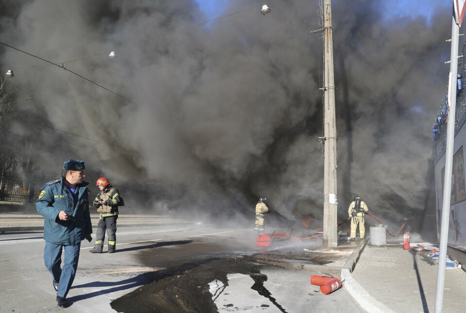 BRANN: Brannfolk i en gate i Donetsk der et kjøretøy ble satt i brann og en butikk fikk skader tirsdag, angivelig som følge av et ukrainsk angrep.