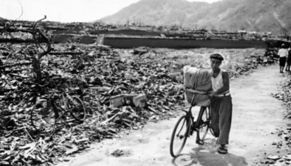 1945: Dette arkivbildet fra september 1945 viser en mann som triller sykkelen sin langs en sti mellom skrotet etter at den japanske byen Nagasaki ble rammet av en atombombe 9. august det året.