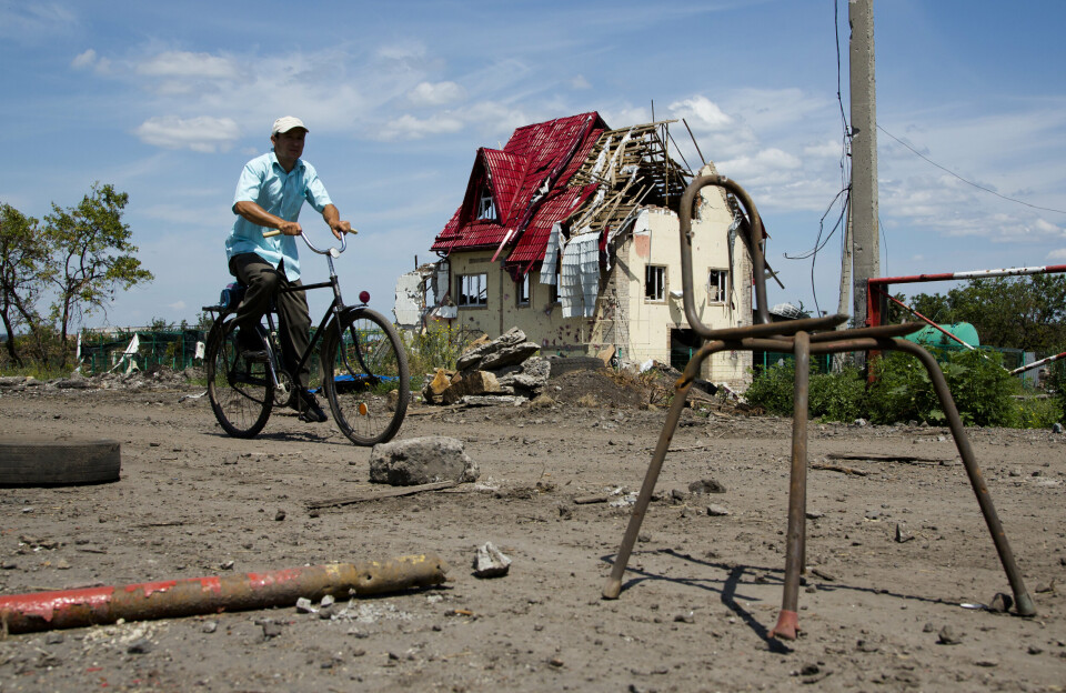 DONBAS: En mann sykler forbi et bombet hus utenfor byen Slovjansk i regionen Donetsk.