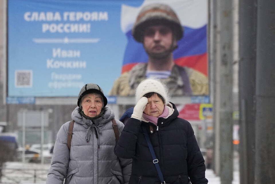 RUSSLAND: To kvinner går forbi et reklameboard i St. Petersburg 31. januar 2023. Plakaten viser en russisk soldat som hylles for sin innsats i Ukraina med setningen: «Heder til Russlands helter.»