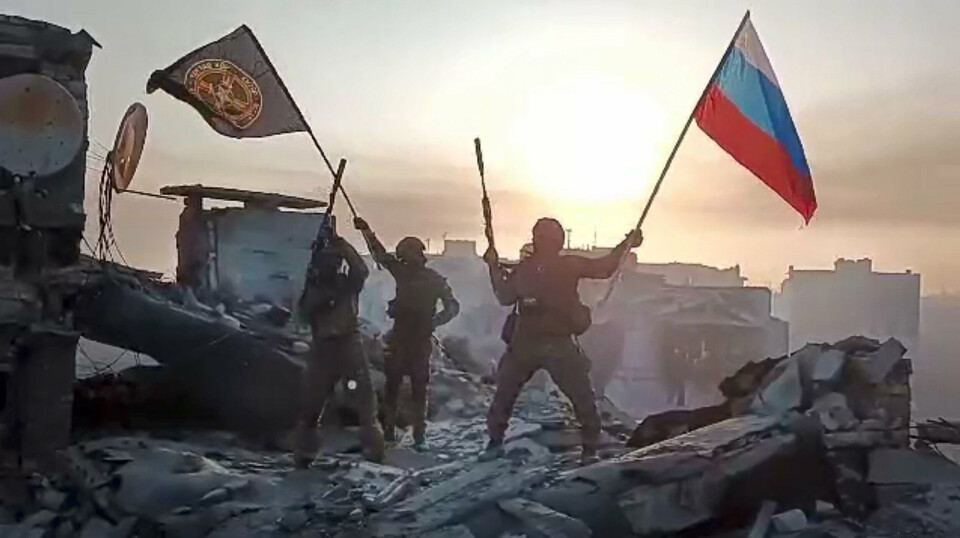 SVEKKET: Russiske soldater med det russiske flagget og Wagner-flagget på toppen av en ødelagt bygning i den ukrainske byen Bakhmut 20. mai 2023. Eksperter mener at Wagners leiesoldater er omtrent ute av stand til å gjennomføre nye offensiver utenfor byen.