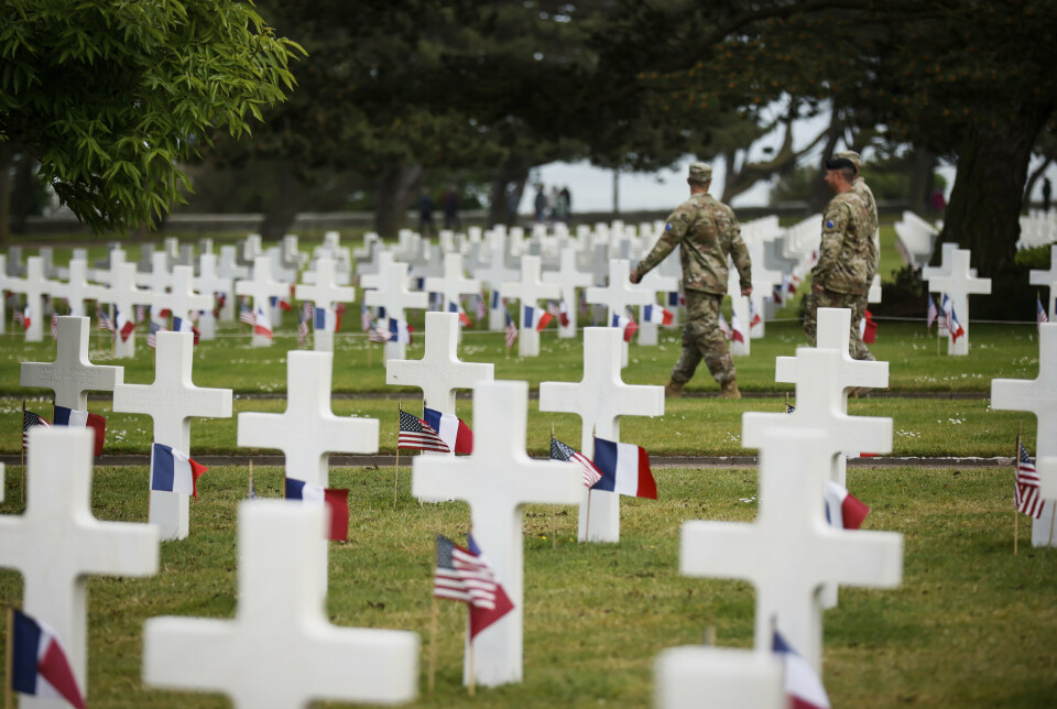GRAVER: To soldater går forbi graver pyntet med franske og amerikanske flagg på den amerikanske krigskirkegården i Colleville-sur-Mer i Normandie. For 79 år siden gikk allierte styrker i land i Nord-Frankrike og begynte frigjøringen av det nazi-okkuperte Vest-Europa.