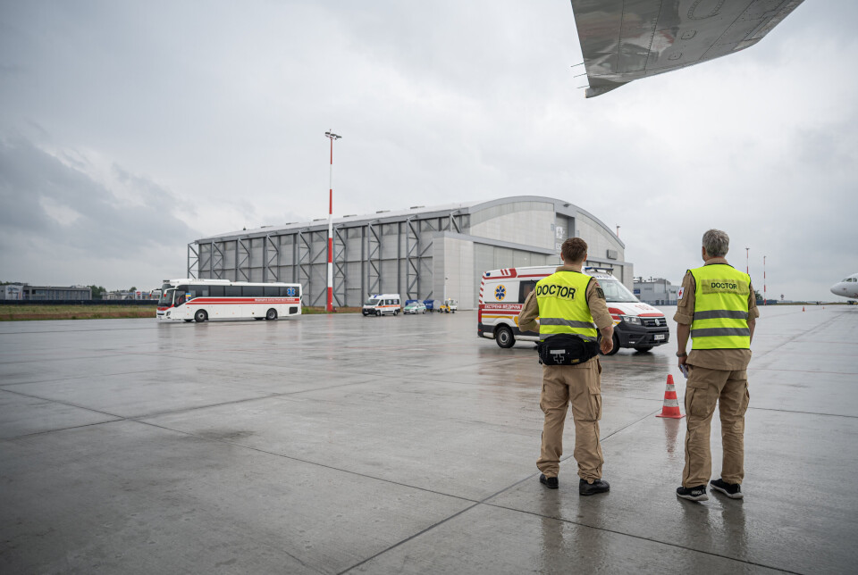MOTTAKELSEN: En del av det norske teamet står utenfor for å ta imot pasientene, mens resten står klare på innsiden av flyet. – Det er et sterkt øyeblikk hver gang når kortesjen med sykebiler og busser kommer kjørende, sier en av flyvertinnene, Brit Myhre.