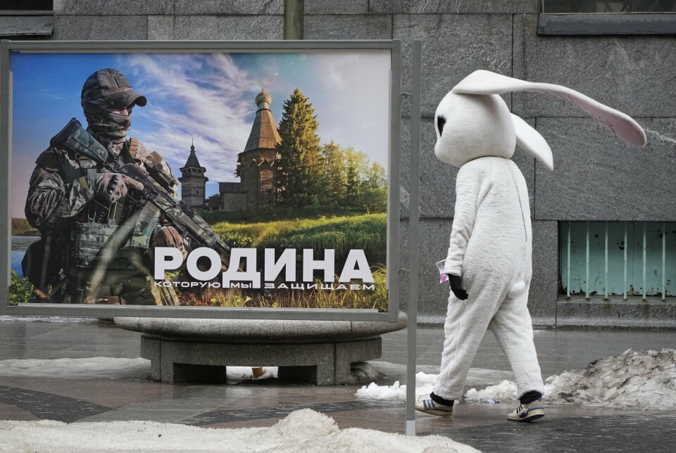 «MODERLANDET»: En gateartist passerer et bilde av en russisk soldat med teksten «Moderlandet som vi forsvarer». Bildet er en del av en utstilling av bilder fra det russiske forsvaret i St. Petersburg. Bildet er tatt 14. mars 2023.