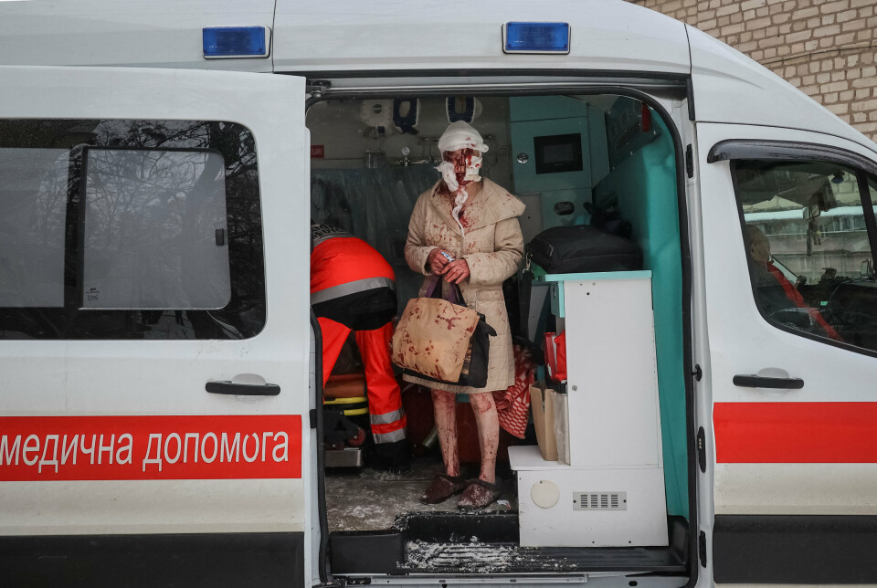 NABOLAG I RUINER: En ukrainsk kvinne står blodig og bandasjert i en ambulanse etter et russisk luftangrep i Kharkiv 23. januar. Veska holder hun fortsatt i handa. På føttene har hun for store tøfler.