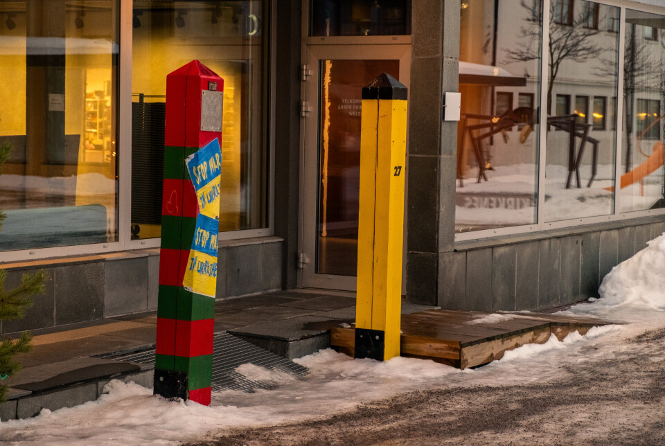 NABOER: Russlands (rød og grønn) og Norges (gul) grensestolper som står side om side langs grensa, er stilt ut i gågata i Kirkenes. Den russiske stolpen har fått påklistret et tydelig budskap mot krigføringen i Ukraina.