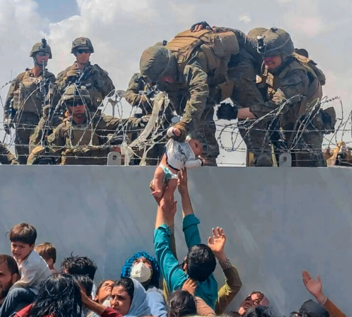 DRAMA I KABUL: En amerikansk soldat får tak i den lille babyen og løftet den over piggtrådgjerdet på flyplassen i Kabul 19. august i fjor. Det lille barnet ble senere tatt hånd om av norske helsearbeidere på feltsykehuset.