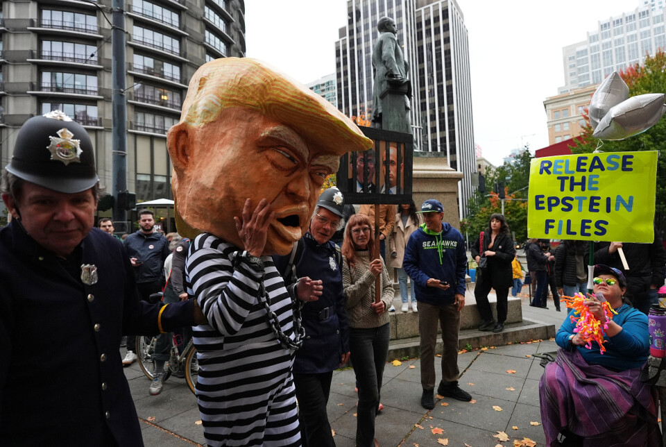 STORE FOLKEMENGDER: En demonstrant har kledd seg ut som president Donald Trump i fangedrakt under demonstrasjonen i Seattle. En annen holder en plakat med krav om at dokumentene fra Epstein-saken blir offentliggjort.