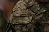 Navnet Koval står på brystet på en militæruniform i grønn pikselkamuflasje