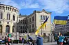 Folk med ukrainske flagg foran Stortinget i Oslo på en klar dag