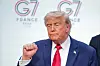 Donald Trump står foran G7-bakgrunn og gjør en knyttet hånd-gest etter mediekonferansen.