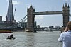 Tower Bridge i London med en båt på Themsen og en person som tar bilde fra høyre side.