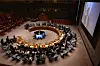 Bredt bilde av et møte i FNs sikkerhetsråd i en halvsirkelformet sal med skjermer og delegater rundt bordet.