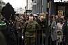 Soldat i unifomr står foran et publikum bak sperringer i en travel gate.